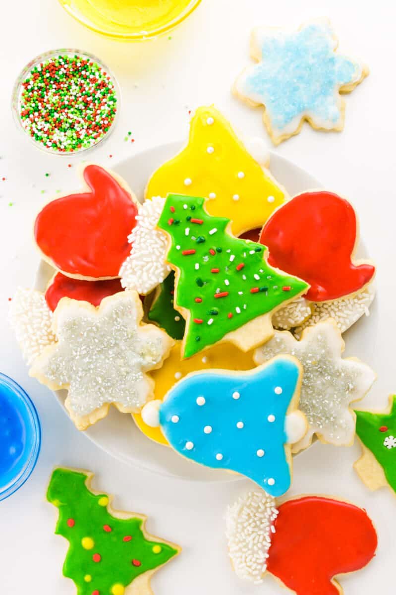 A number of holiday themed Vegan Sugar Cookies are on a white counter top.