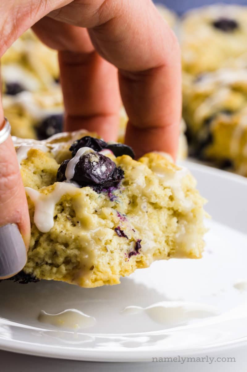 A hand holds a scone with a bite taken out of it.