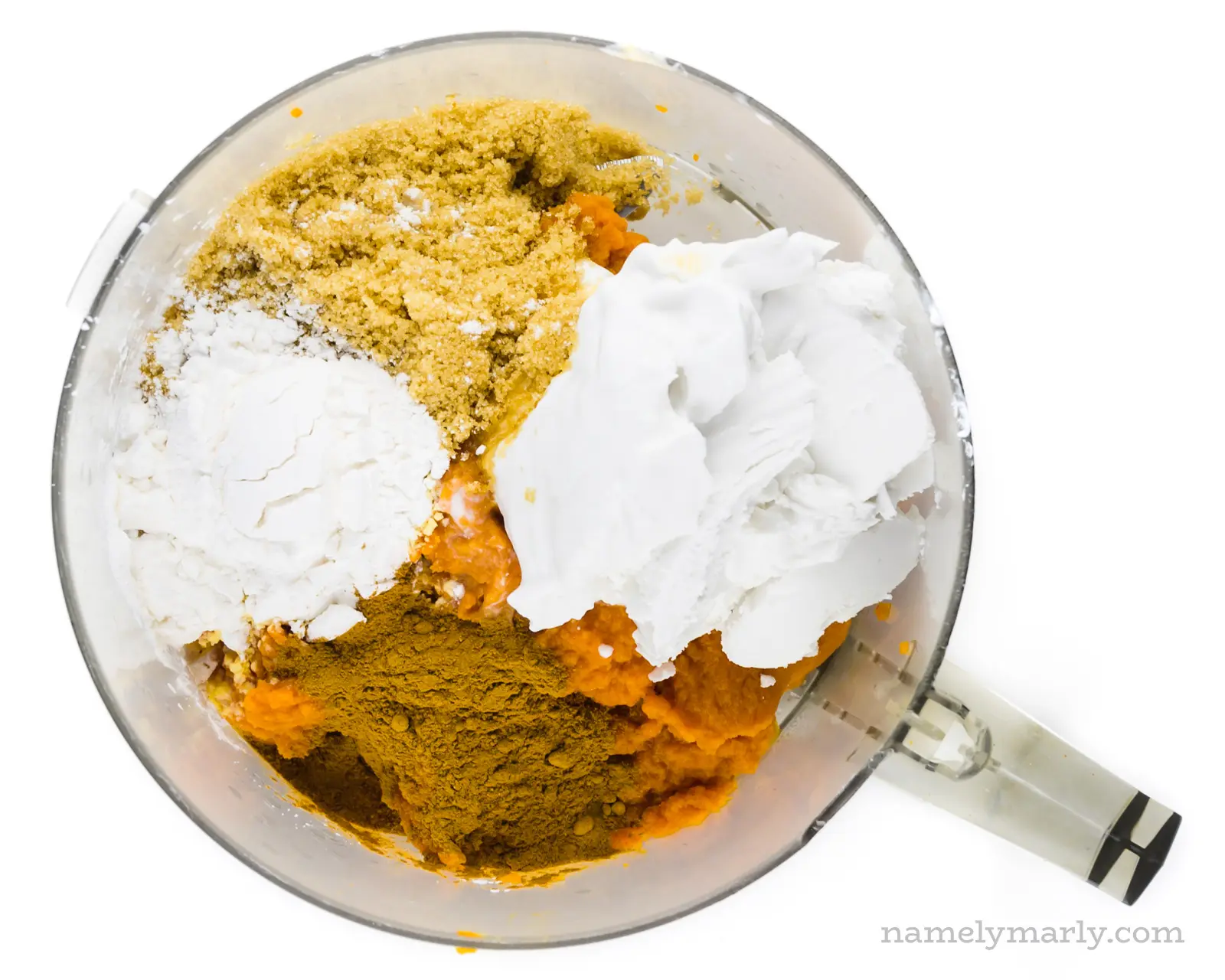 Ingredients like coconut milk, brown sugar, and spices are in a food processor bowl.