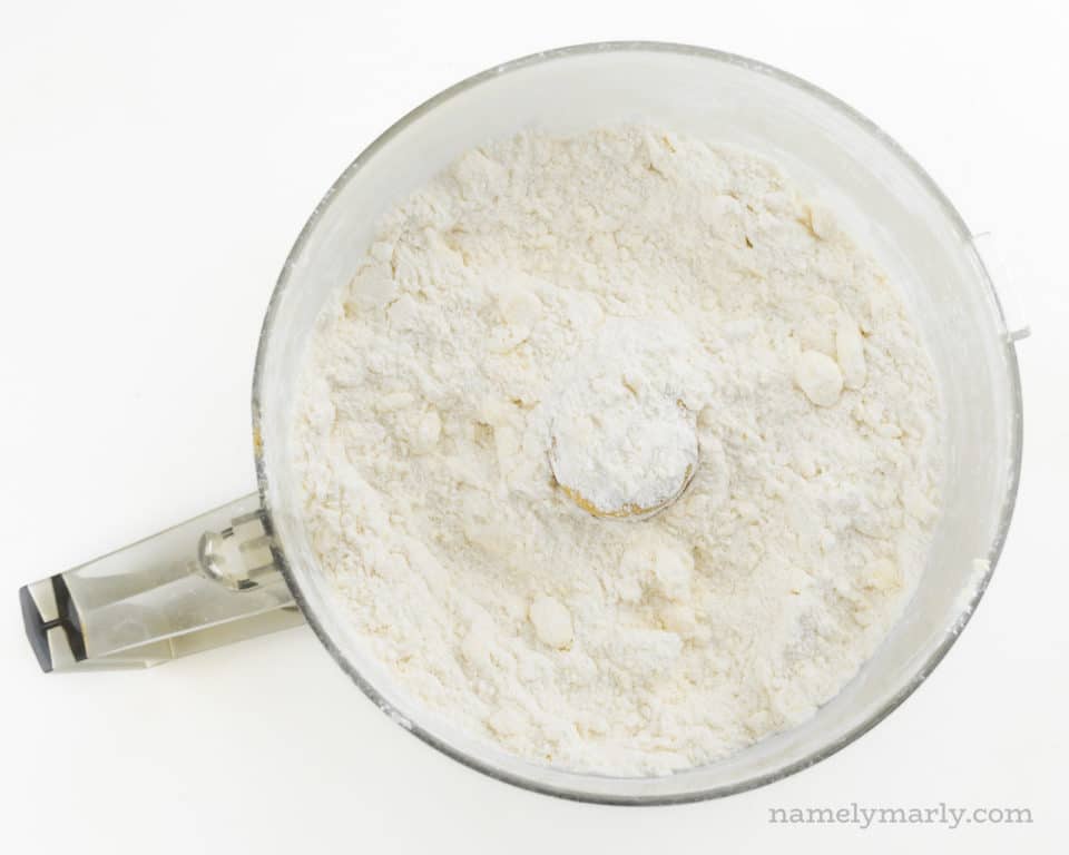 Looking down on a food processor bowl full of flour and bits of butter.