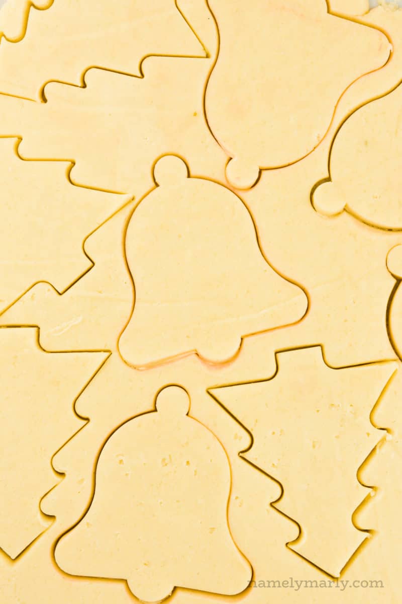Rolled cookie dough has been cut into shapes using Christmas cookie cutters.