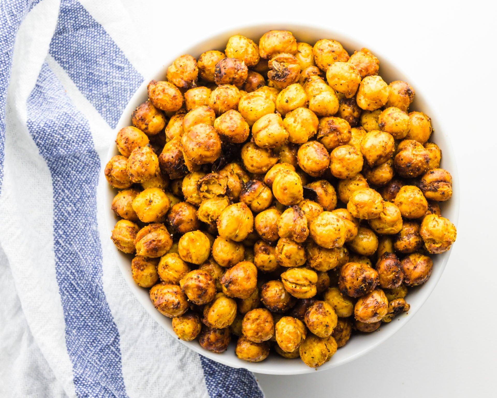 Looking down on a bowl of chickpeas next to a kitchen towel.