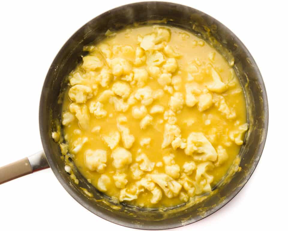 A skillet is full of cauliflower cooked in a gravy-like sauce.
