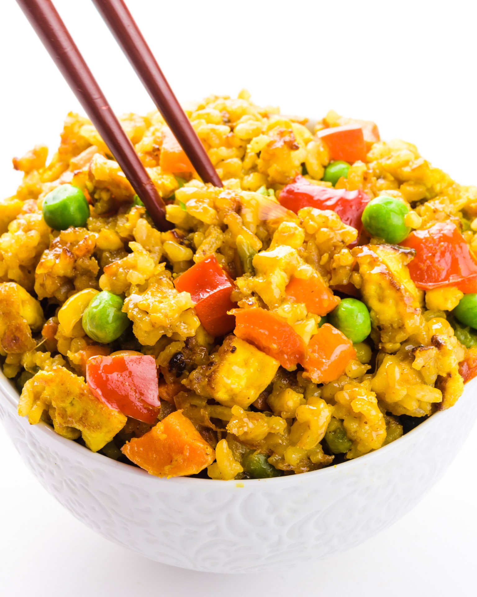 Chopsticks are reaching into a bowl full of fried rice.