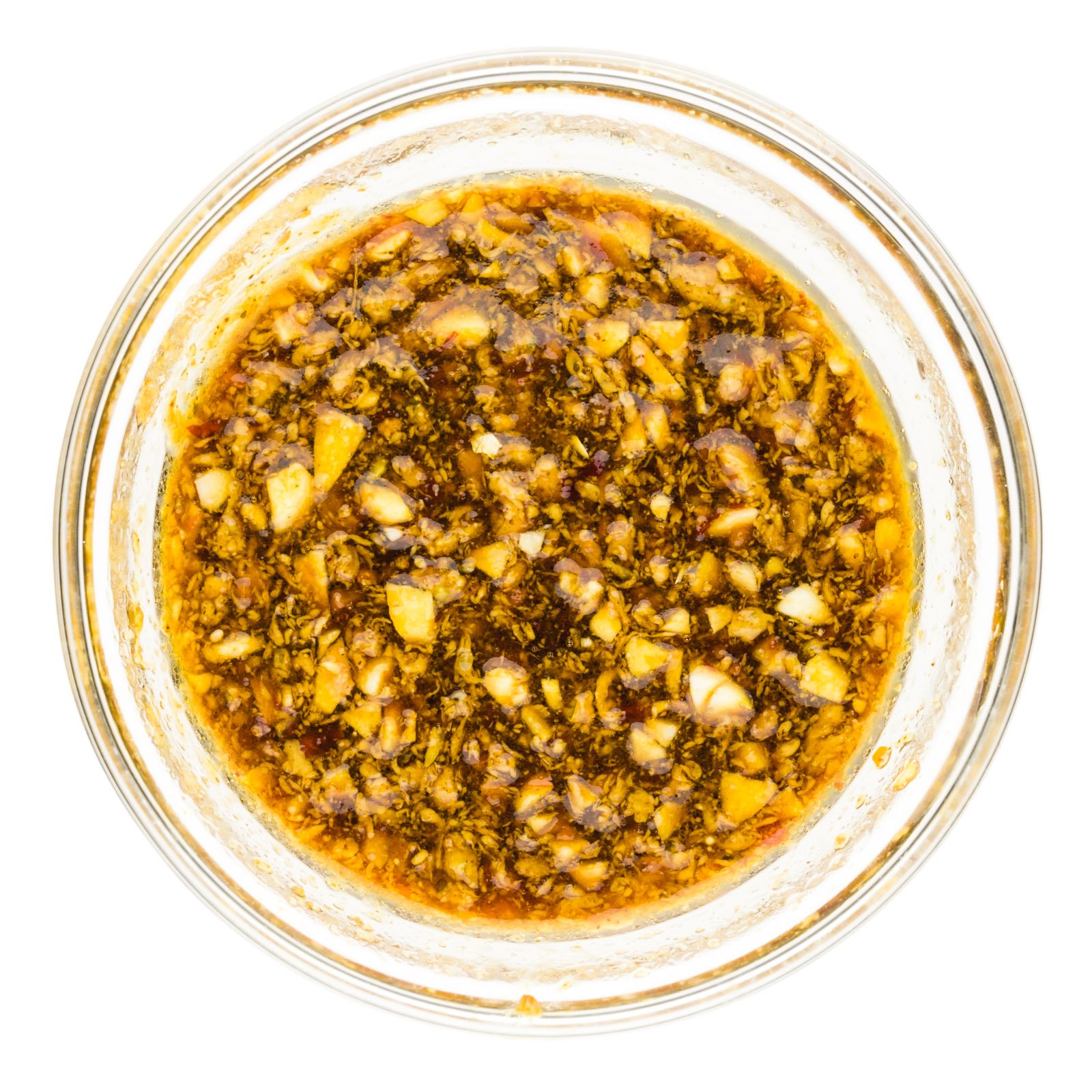 A glass bowl holds a mixture of soy sauce, chopped garlic, and more seasonings.