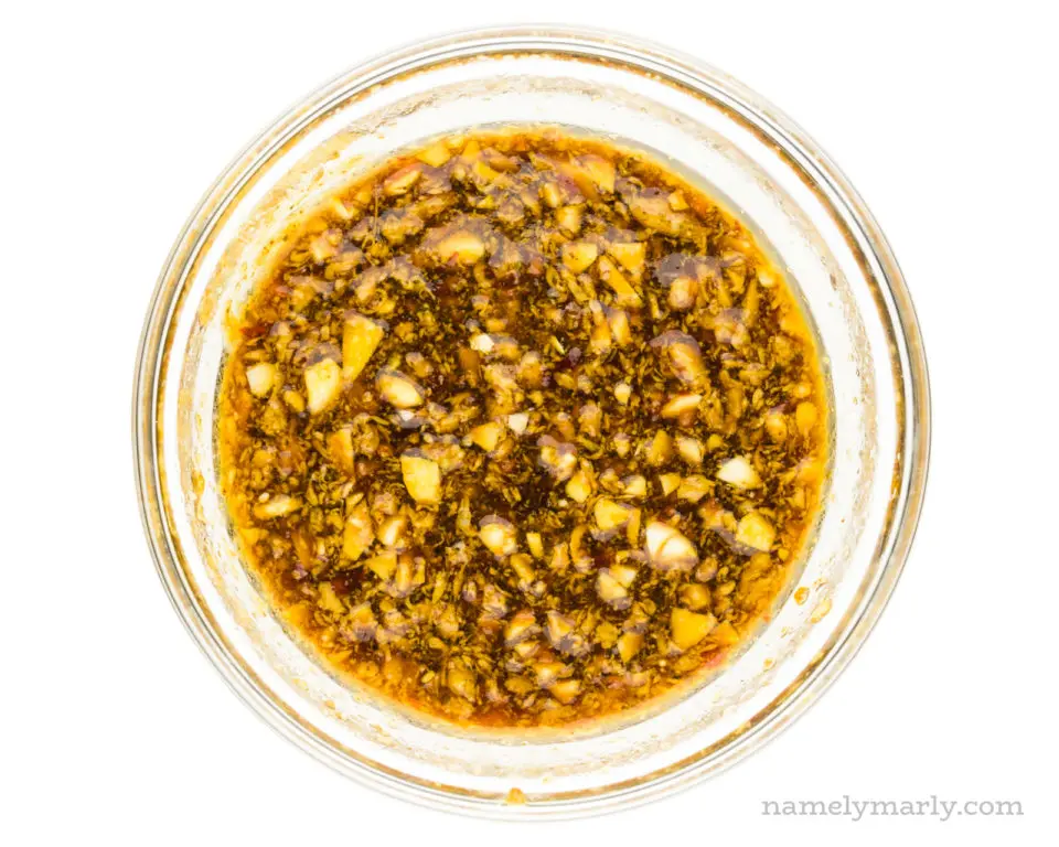 A glass bowl holds a mixture of soy sauce, chopped garlic, and more seasonings.