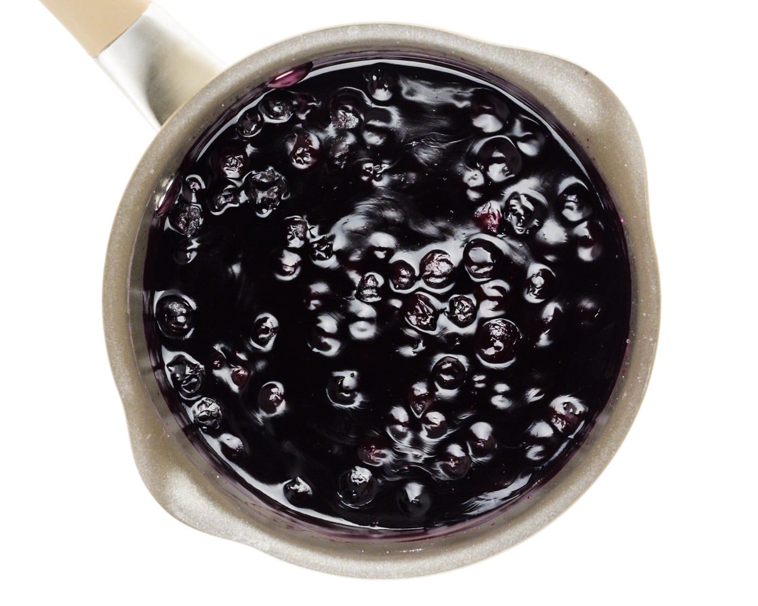 Blueberry sauce is cooking in a saucepan.