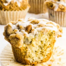 A cinnamon muffin with a bite take out sits in front of other muffins.