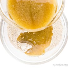 A bowl full of liquid ingredients is being poured into a bowl full of flour ingredients.