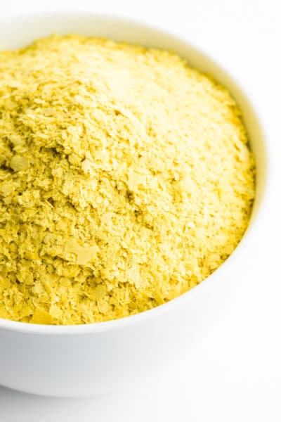 A bowl is full of yellow nutritional yeast flakes.