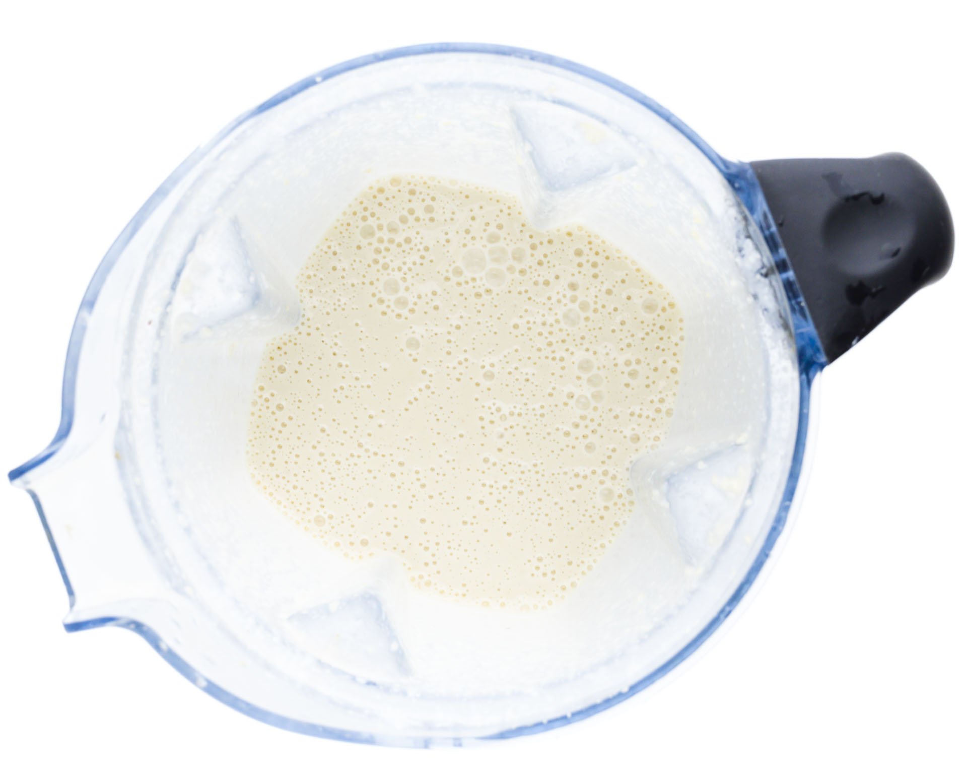 A blender jar has vegan freshly whipped alfredo sauce in it.