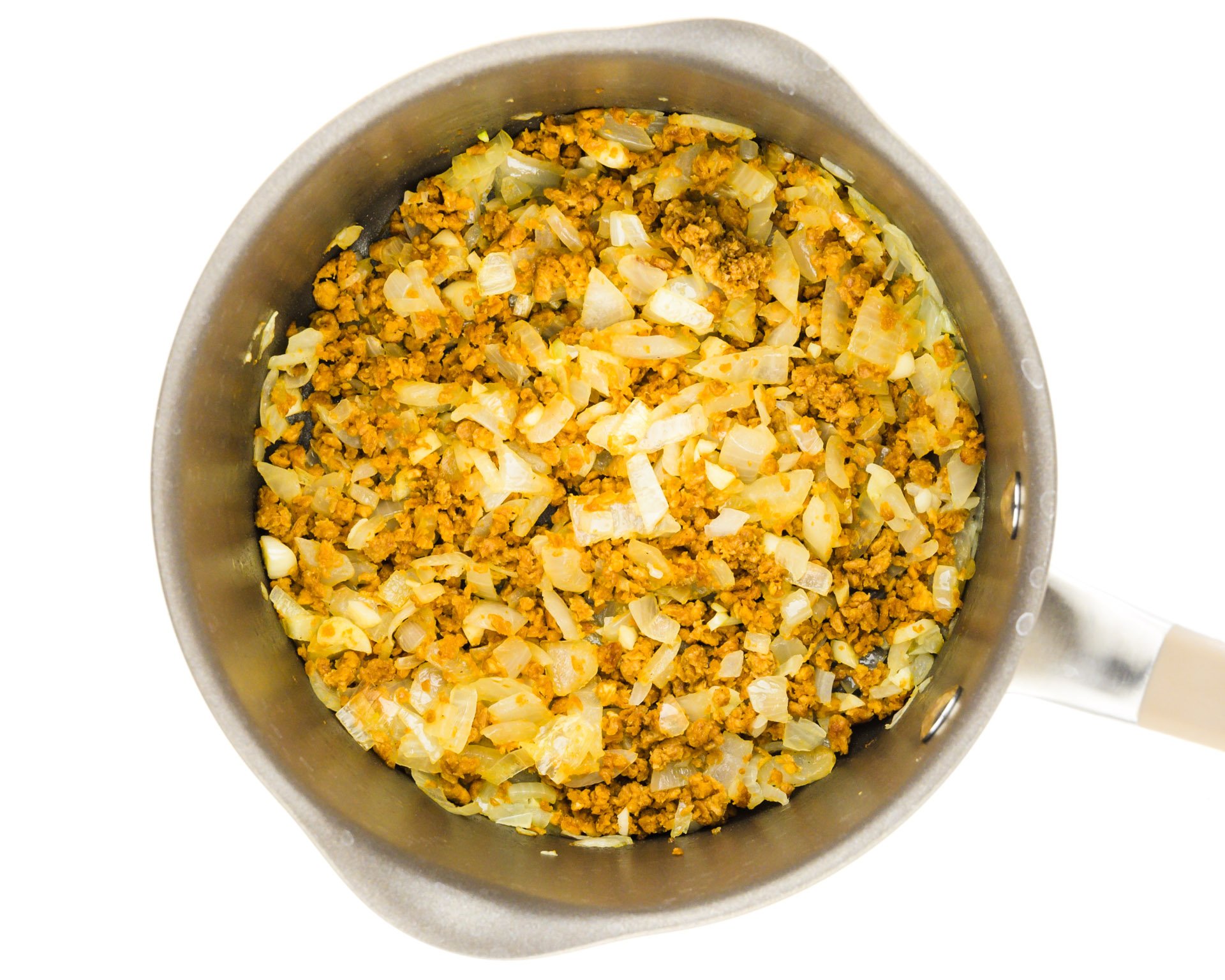 A saucepan holds onions, garlic, and veggie crumbles.