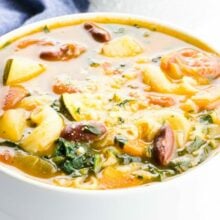A closeup of minestrone soup with another bowl behind it.