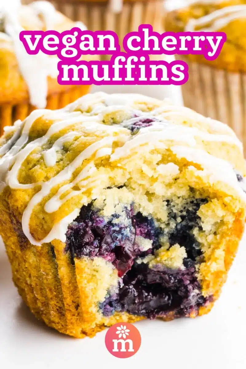 A muffin with a bite taken out sits on a white counter. The text reads, Vegan Cherry Muffins.