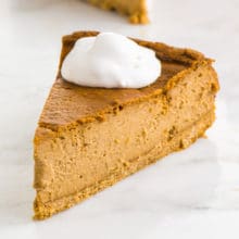 A slice of vegan pumpkin cheesecake have whipped cream on top