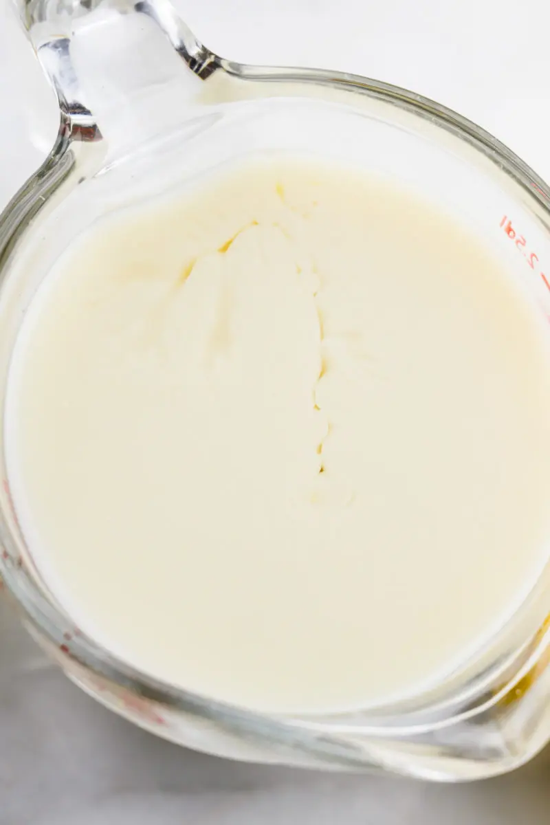 Looking down on a glass of plant-based milk that is beginning to separate because lemon juice has been added.