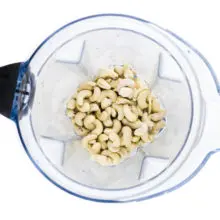 Cashews are in the bottom of a blender jar, waiting to be processed.