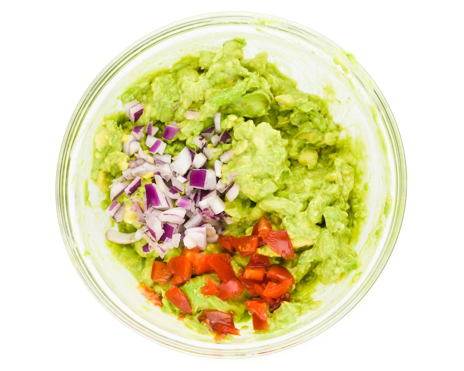 Chopped red onions and chopped cherry tomatoes have been added to mashed avocados.