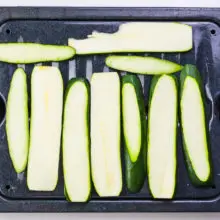Zucchini slices are on a roasting pan.