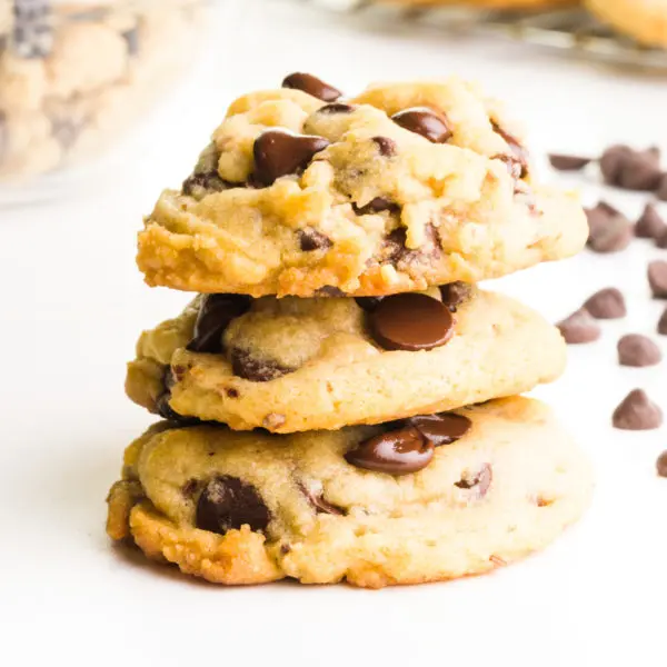 A stack of chocolate chip cookies have chocolate chips around them.