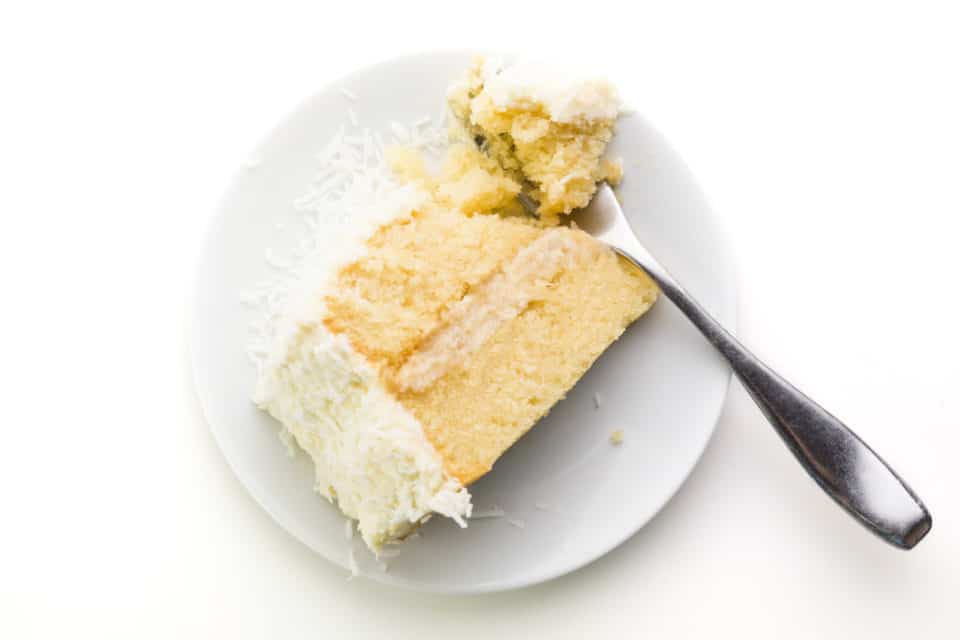 Looking down on a slice of cake on a plate with a fork holding a bite.