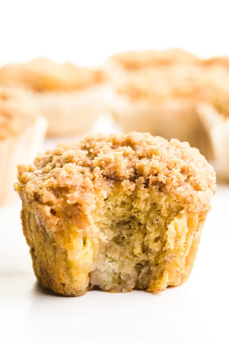 A banana muffin has a bite taken out of it and sits in front of other muffins.