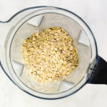 Oats are in the bottom of a blender jar.