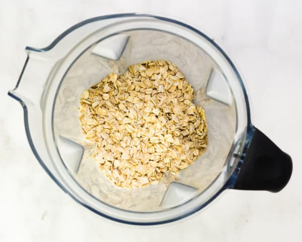 Oats are in the bottom of a blender jar.