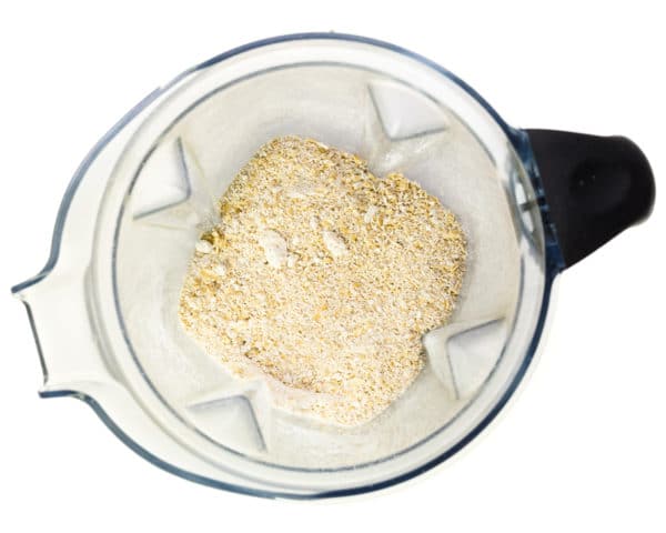Blended oat flour is in the bottom of a blender jar, having recently been blended.