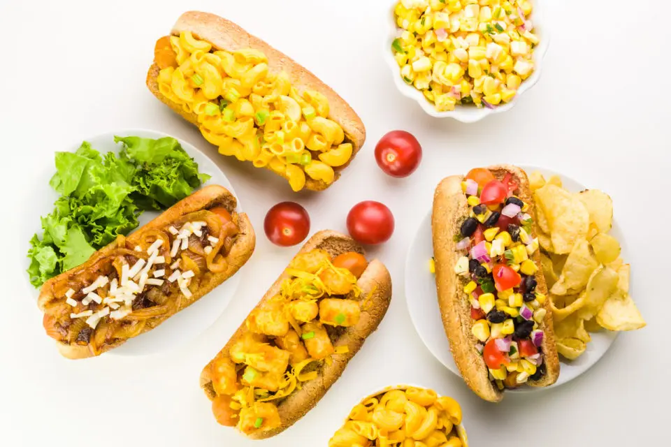 Looking down on four vegan hotdogs all with different toppings, like black beans, tater tots, and more.