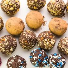Looking down on several rows of vegan truffles, all with different toppings, like nuts or sprinkles.