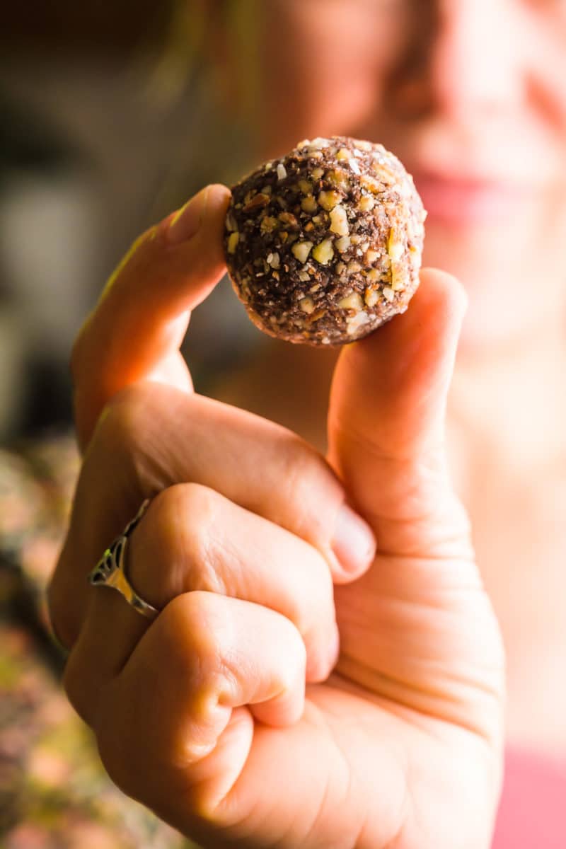 A woman holds a truffle out in front of her. Her face, along with the rest of the background, is out of focus.