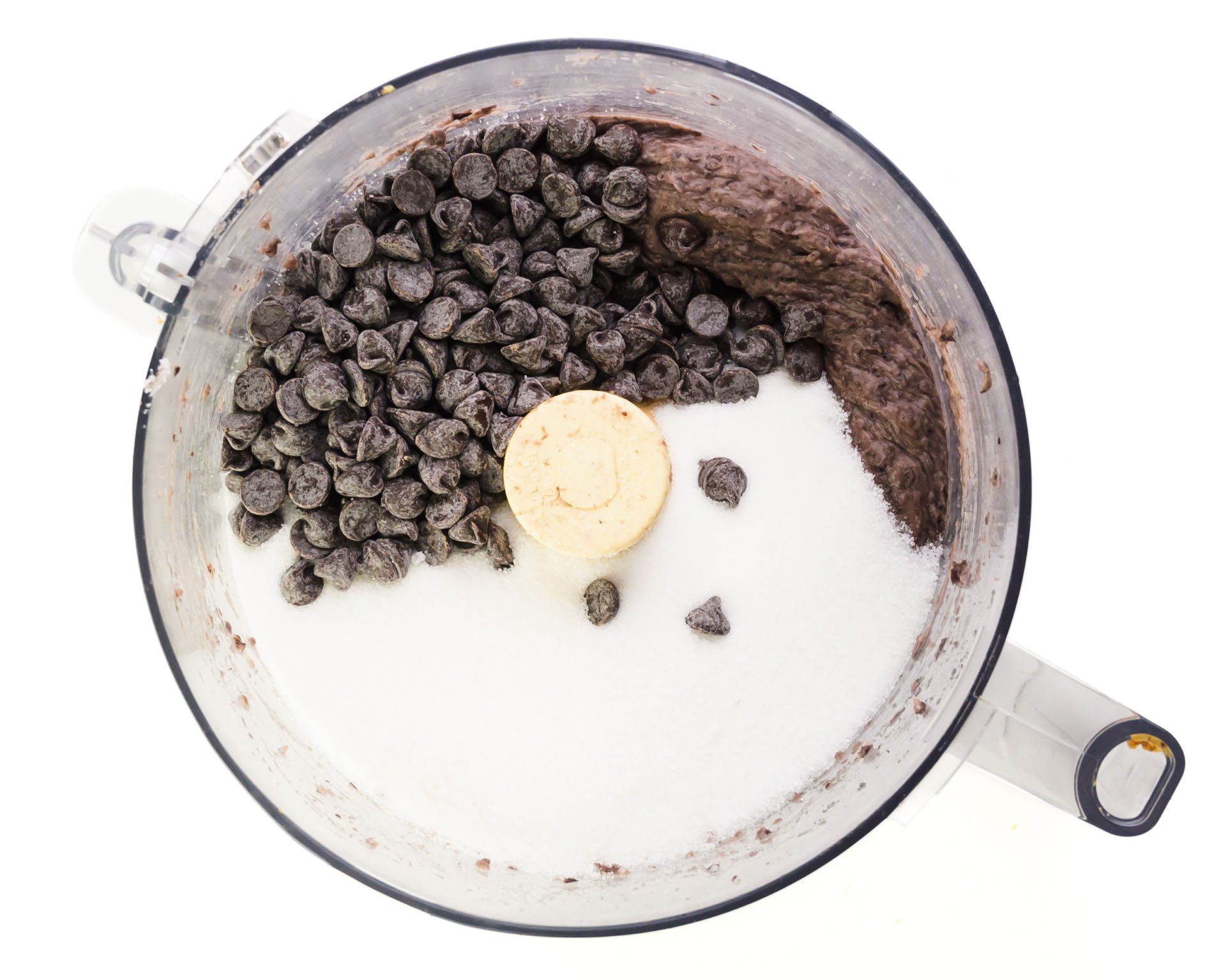 Blended black beans, chocolate chips, and sugar is in the bottom of food processor bowl.