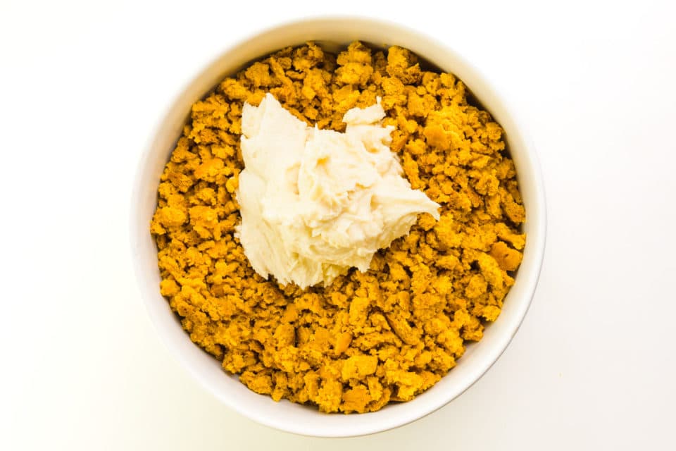 Cake crumbs are in a bowl along with vanilla frosting.