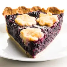 A slice of elderberry pie on a plate.