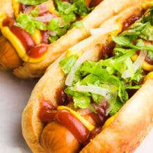 Two vegan hot dogs have hot dogs inside with toppings like ketchup and mustard.
