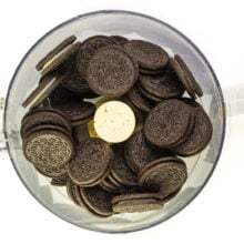 Several chocolate sandwich cookies are in the bottom of a food processor bowl.
