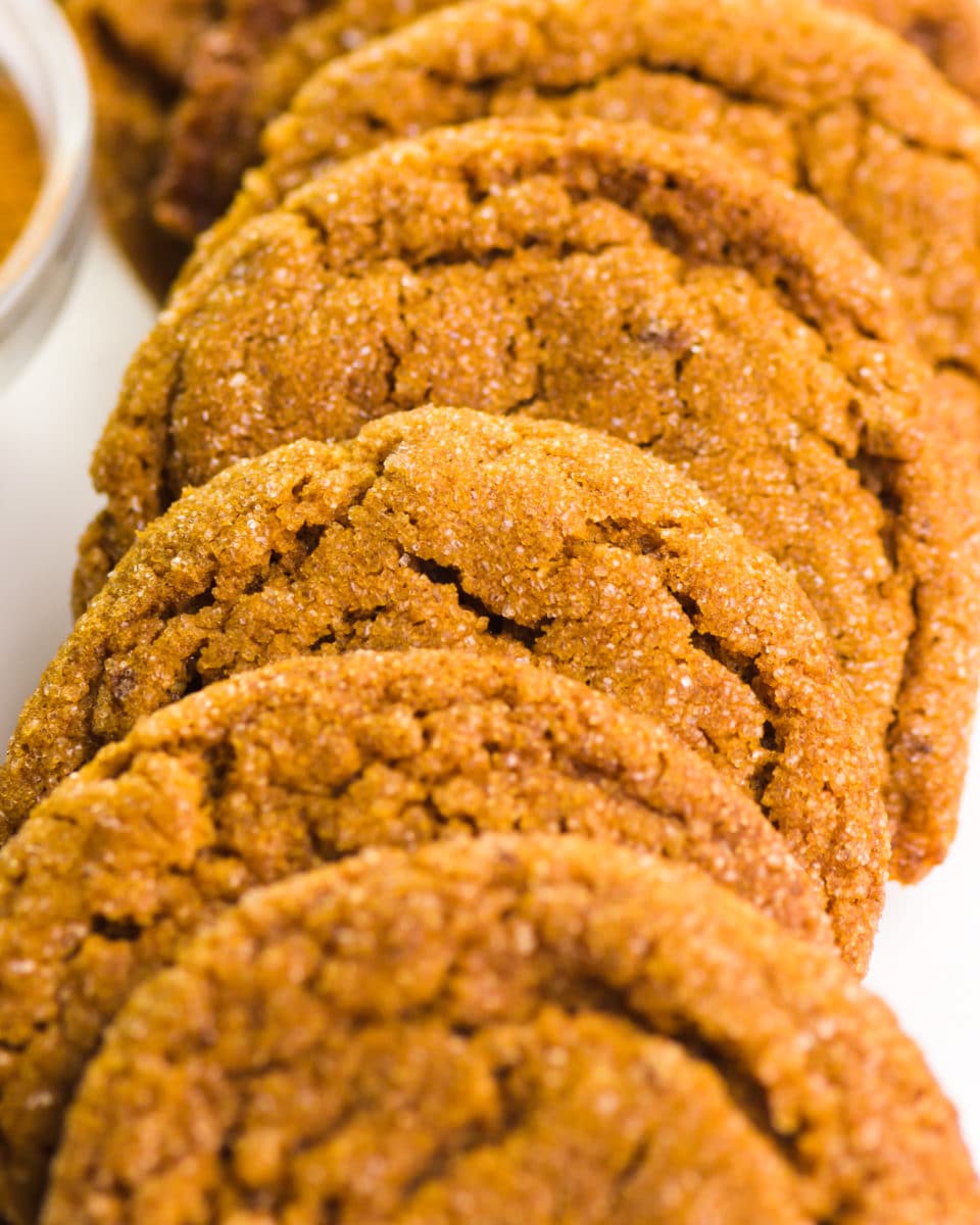 A row of cookies sits next to a bowl of ground cinnamon.