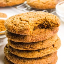 A stack of soft molasses cookie shows the top one with a bite taken out. There are more cookies behind the stack.
