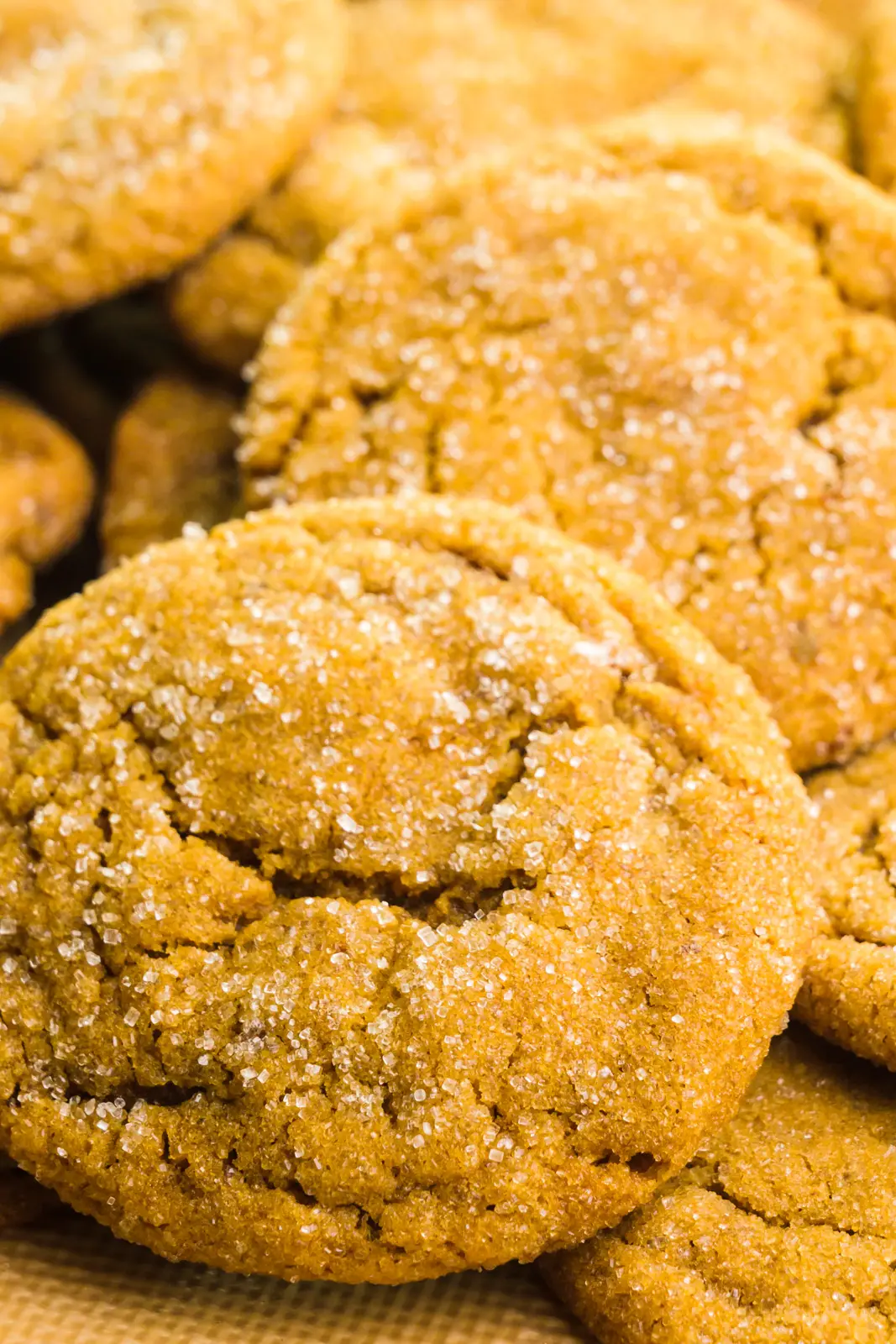 A close-up of several cookies with crackly tops and sugar on top.