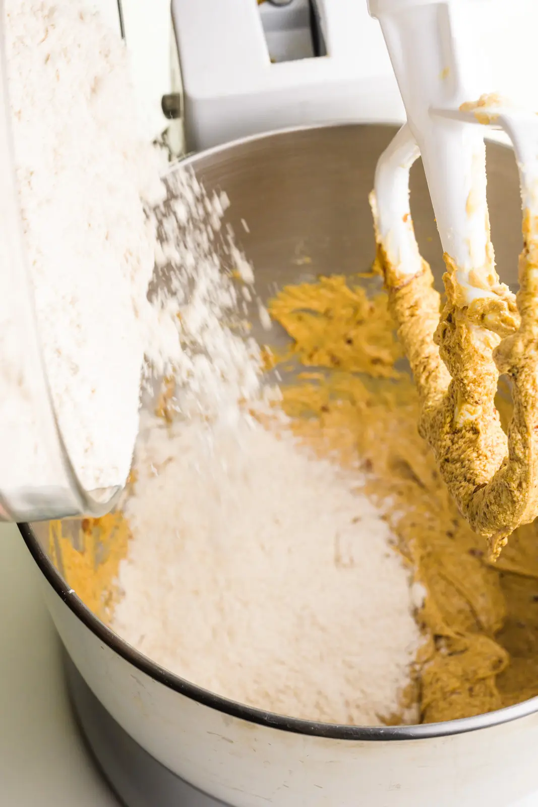 Flour is poured into a mixing bowl with cookie dough.