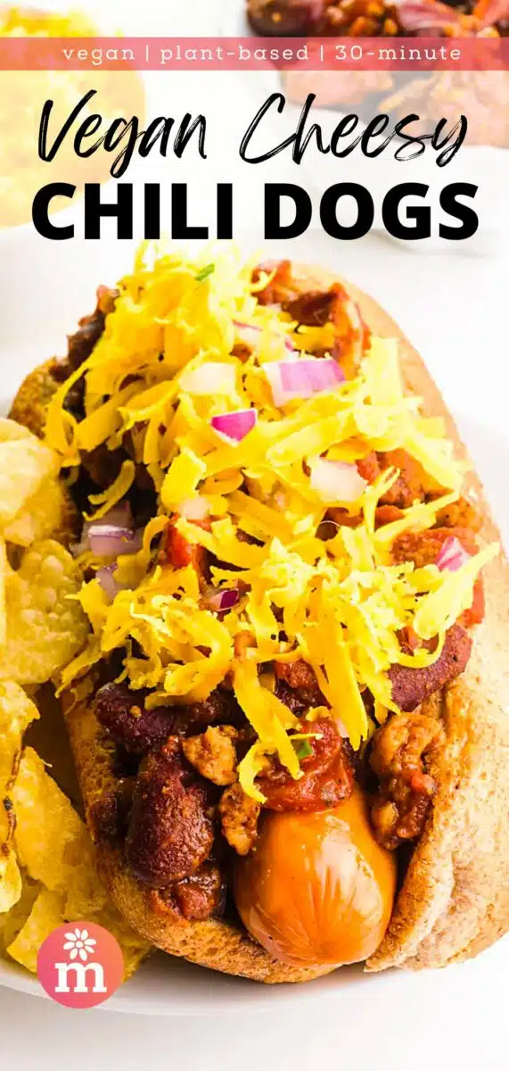 A chili dog in a bun sits on a plate in front of other ingredients. The text reads, vegan, plant-based, 30-minute Vegan Cheesy Chili Dogs.