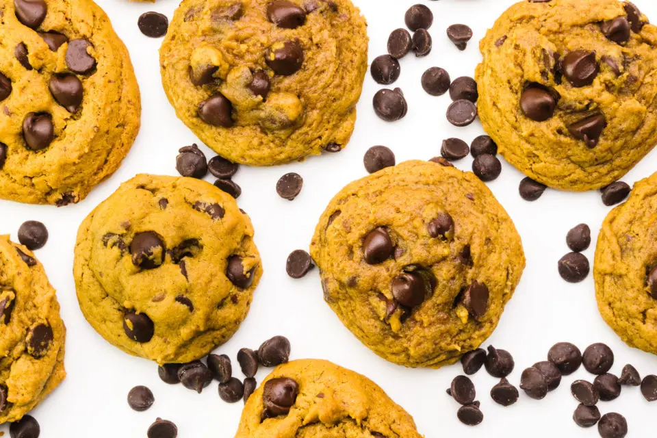 Looking down on several cookies on a white background. There are chocolate chips between the cookies.