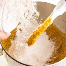 Flour is poured into a mixing bowl with a pumpkin mixture.