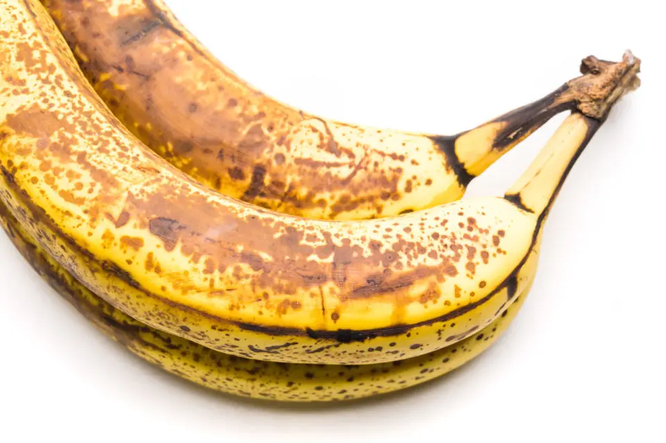 A bunch of 3 very ripe bananas sit on a white counter.