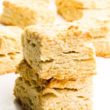 A stack of rectangle vegan biscuits sits in front of other biscuits in the background.