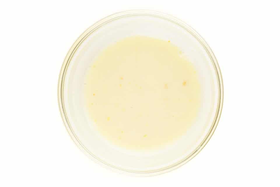 A bowl has soy milk inside being curdled with vinegar.