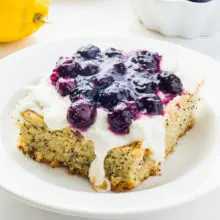 A slice of lemon avocado cake with blueberry sauce on top sits on a plate