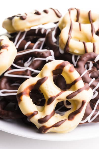 Vegan chocolate covered pretzels sits on a white plate.