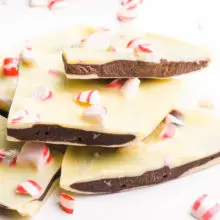 A stack of peppermint bark has pieces of peppermint around it.